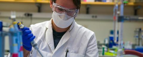 Female student in lab coat working on project