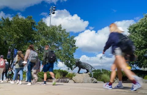 students walking by wildcat statue
