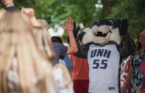 New UNH students high-fiving Wild E. Cat at orientation