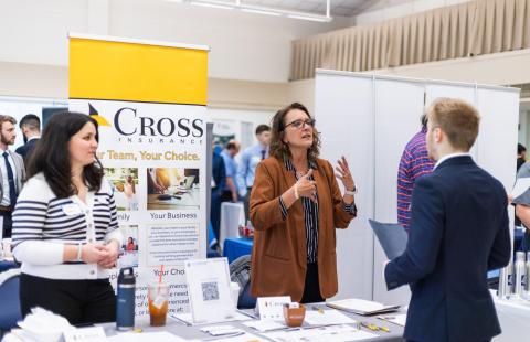UNH student talking to representatives from Cross Insurance at the Career and Internship Fair