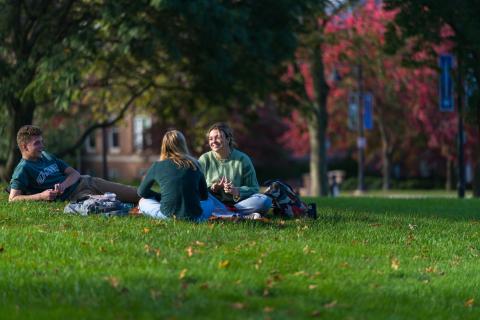 UNH students sitting outdoors on campus