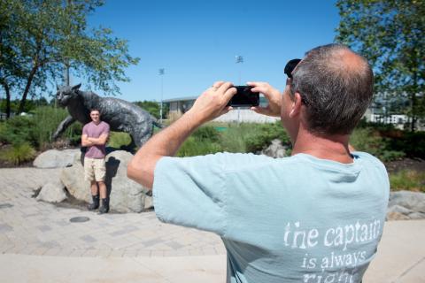 UNH father taking photo of son in front of Wildcat statue