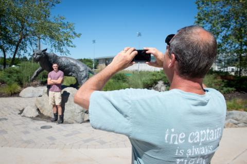 UNH father taking photo of son in front of Wildcat statue 