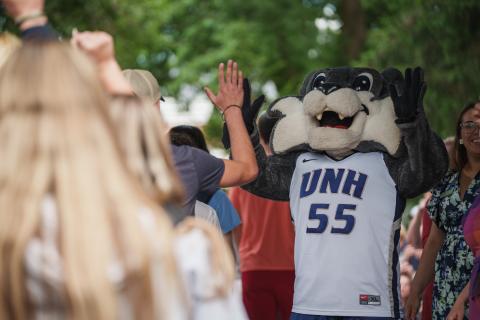 New UNH students high-fiving Wild E. Cat at orientation